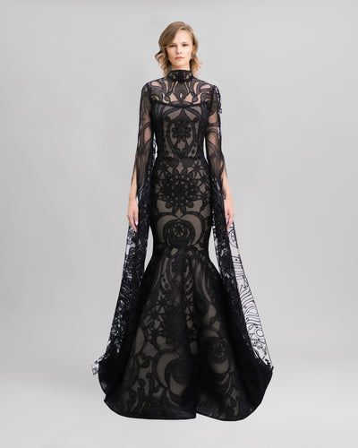 A strapless mermaid-cut black patterned lace evening dress with a flared tail, and a detachable top with floor length sleeves.