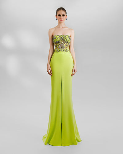 An evening wear set featuring a strapless sheer corset lime top with full beadings on it and a long lime crepe skirt with a middle slit, a little bit of train and a trumpet silhouette.