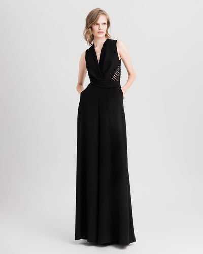 A cowl-neckline black jumpsuit with crochet lace on the sides and back, and a flared cut.