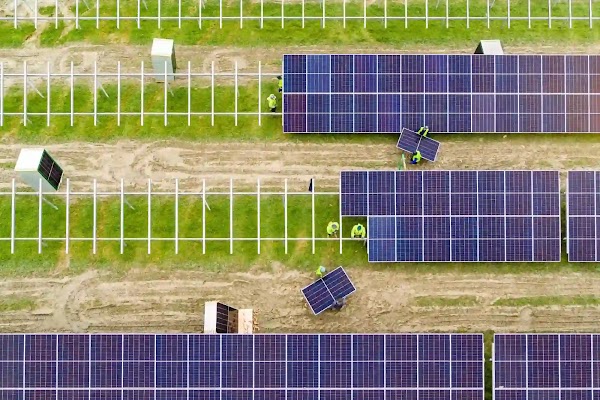 Un groupe d'ouvriers assemblent une rangée de panneaux solaires dans un champ verdoyant