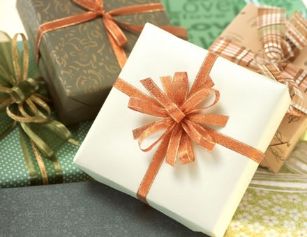 green, cream, gold and pumpkin colored wrapped boxes with ornate ribbons in burnt sienna, green and gold and brown, white and burnt sienna plaid ribbon