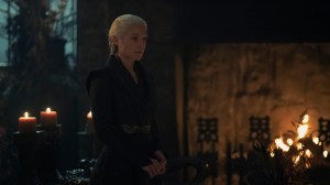 A female-presenting figure in black medieval clothing standing in a candlelit room; still from 'House of the Dragon'