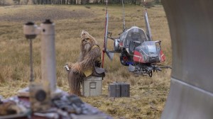 Wookie Jedi Master Kalnacca (Joonas Suotamo) sites on a box in a field fixing machine parts with a speeder bike behind him in Episode 3 of Disney+ series 'The Acolyte'