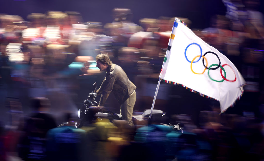 PARIS, FRANCE - AUGUST 11: American Actor and Film Producer Tom Cruise rides on a Motorbike with the IOC Flag during the Closing Ceremony of the Olympic Games Paris 2024 at Stade de France on August 11, 2024 in Paris, France. (Photo by Steph Chambers/Getty Images)