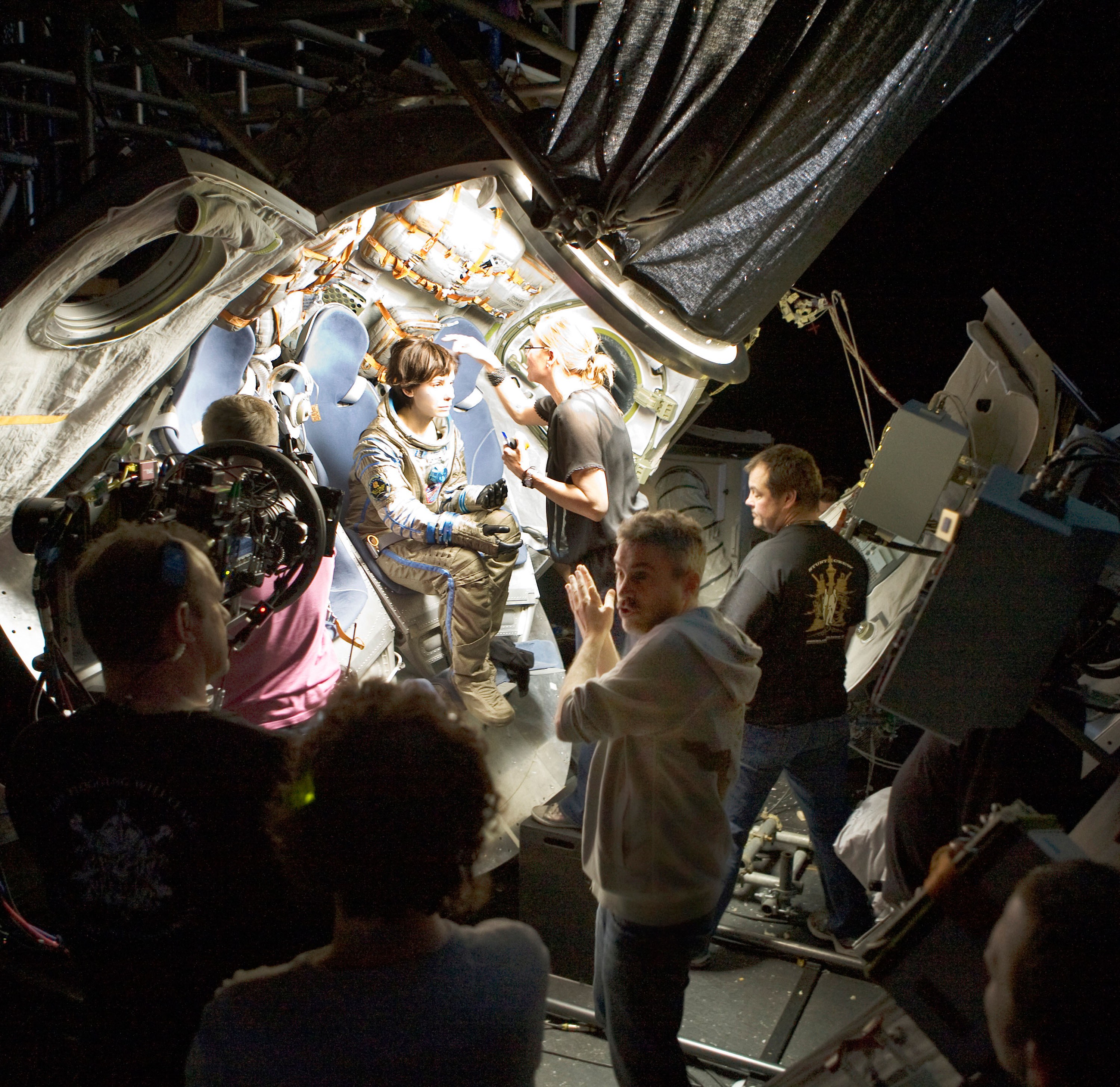 'GRAVITY,' Sandra Bullock (sitting, center), director Alfonso Cuarón (front, center), on set, 2013. ©Warner Bros. Pictures/courtesy Everett Collection