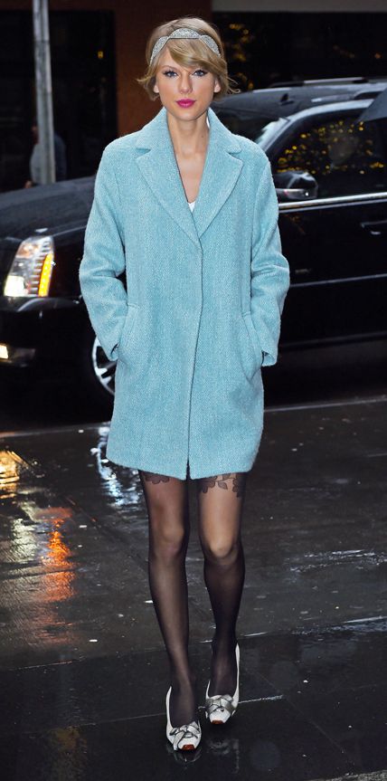 Taylor Swift in a powder blue coat, sheer black stockings, and sparkly headband