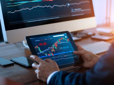 Businessman checking stock market on digital tablet and a desktop computer with stock exchange graph on screen. Financial stock market. Analyzing data in office background.