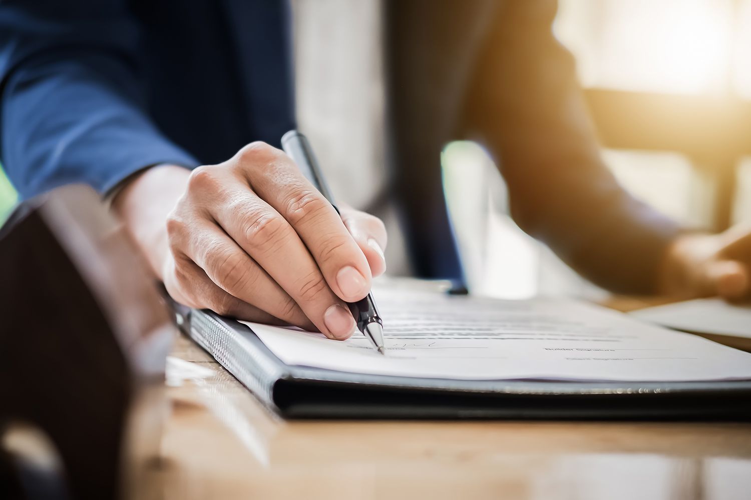 Businessperson reviews and signs documents in an office.