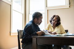 A retired couple reading over financials together at a table.