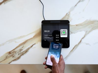 Cropped hand of customer tapping smartphone on point-of-sale (POS) system in coffee shop