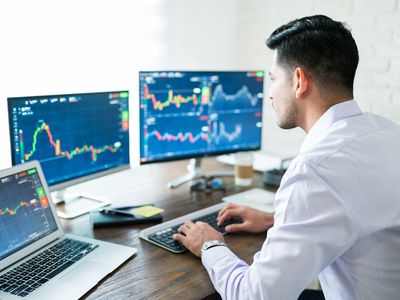 Hispanic young male stock trader typing on keyboard while using computer at home