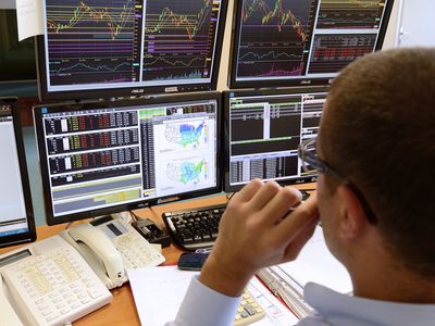 Trader looking at several monitors with stock market information