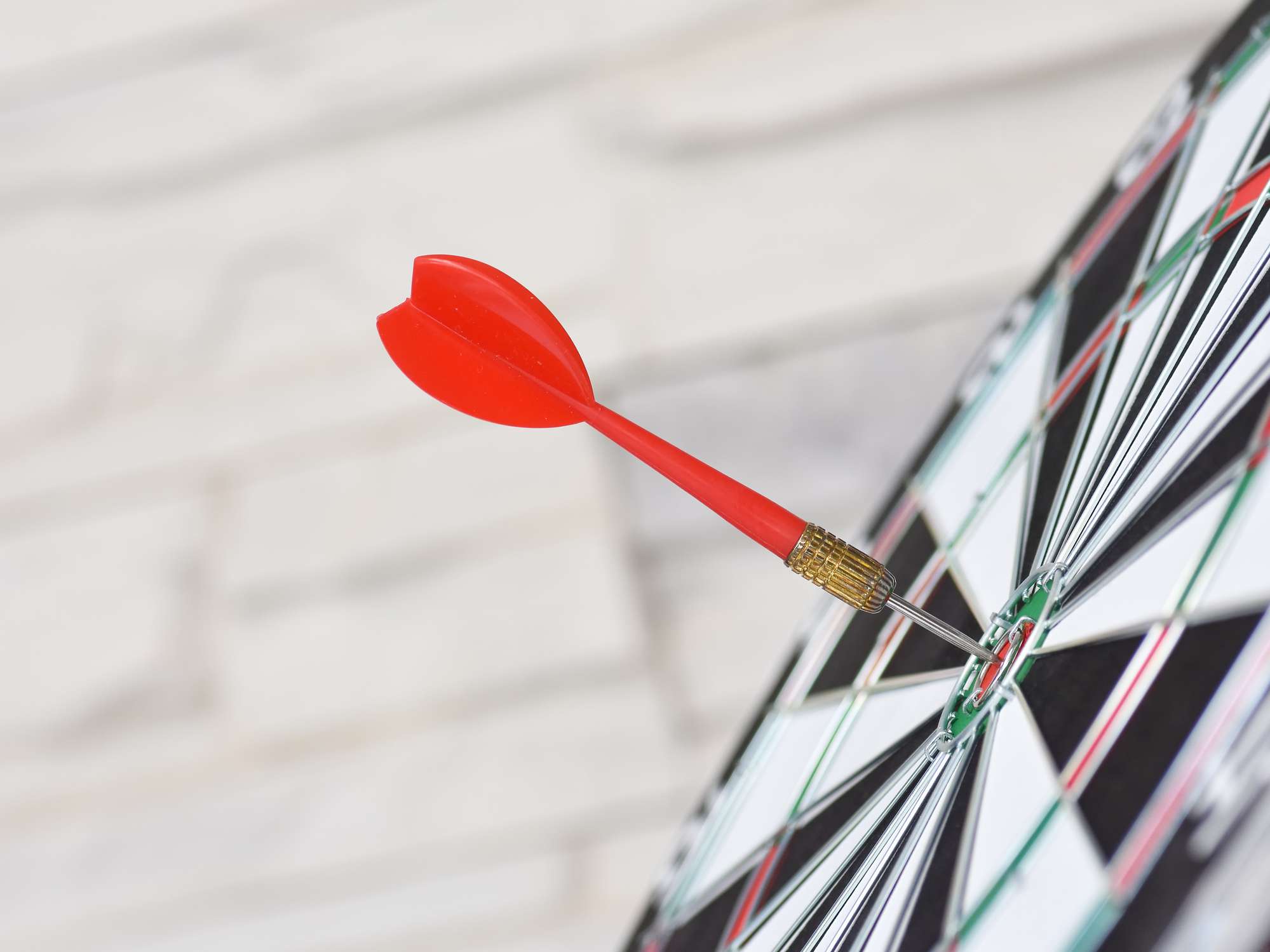 A dart arrow hitting in the target center of a dartboard.