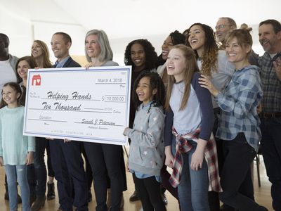 Enthusiastic community posing with large donation check