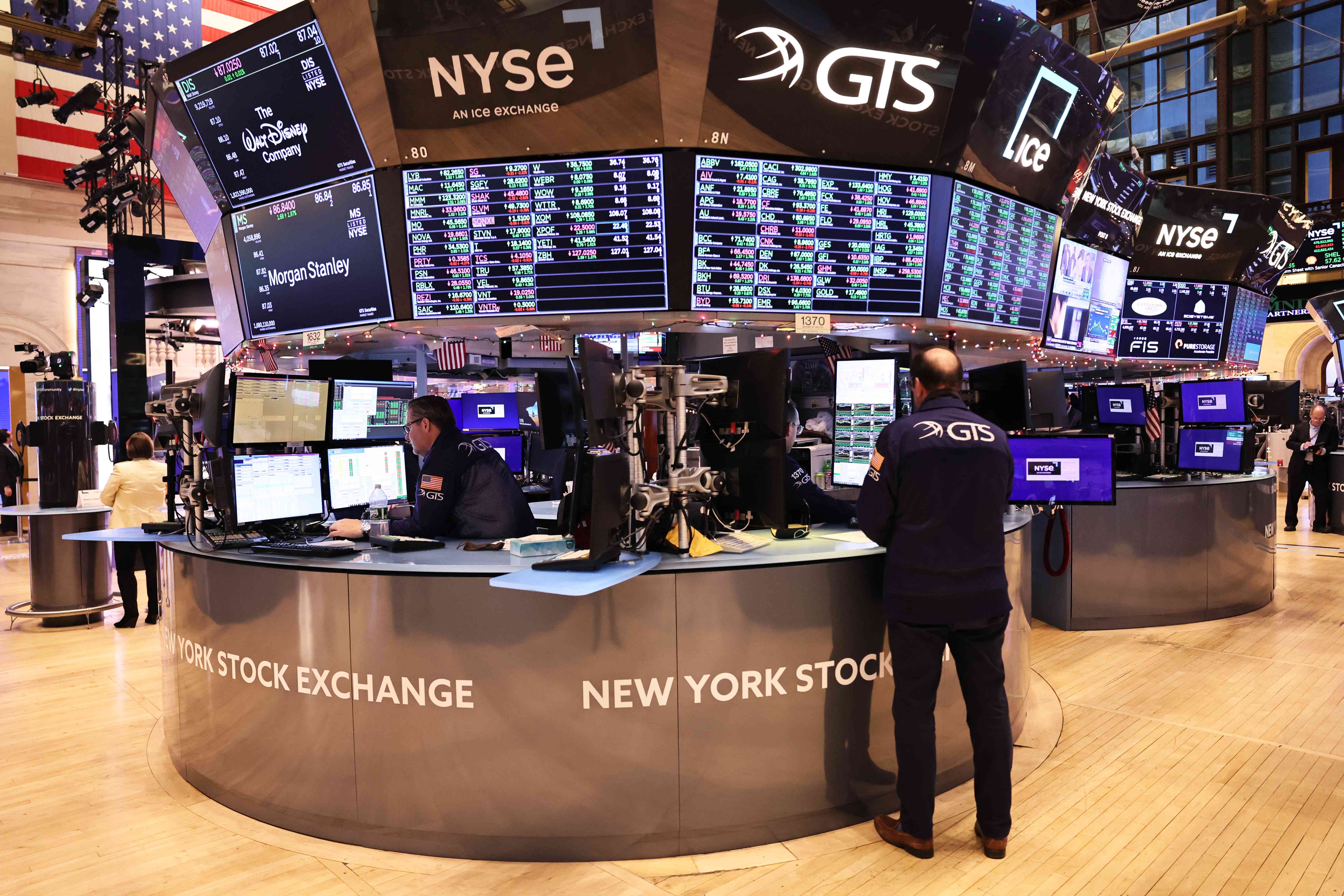 Traders stand beneath financial monitors on the floor of the New York Stock Exchange