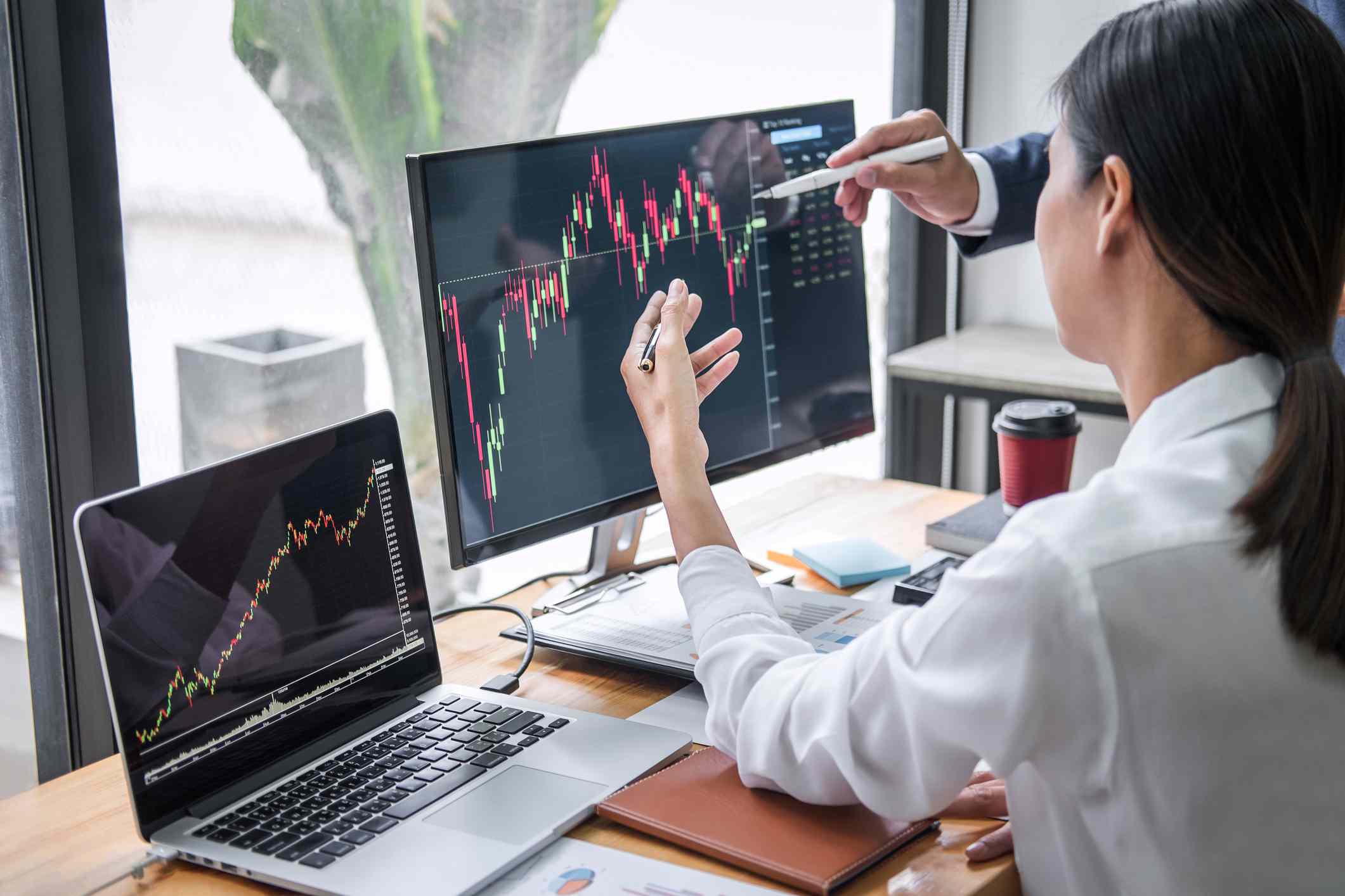 woman at desktop looking at financial charts