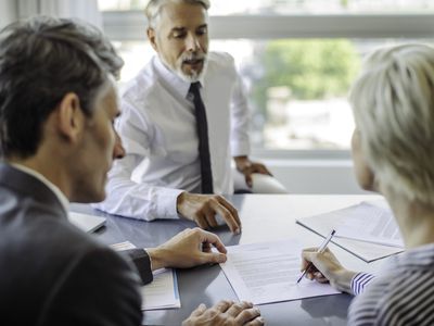 An insurance agent explaing the surrender fee for insurance policy with a couple before they sign the documents.