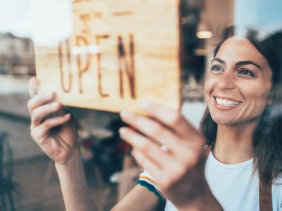 Happy business owner hanging an open sign on the door at a cafe