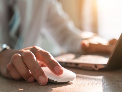 Businessman hand holding computer mouse with laptop keyboard