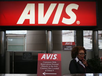 An employee speaks on a telephone at a rental counter for Avis Budget Group at an airport. 