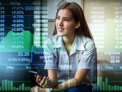 A businesswoman sitting on working space and looking the Stock market exchange information and Trading graph in the modern Office.