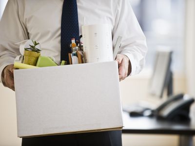 A person holding a box full of office supplies