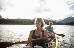 Mature couple canoeing on tranquil lake in Alberta, Canada