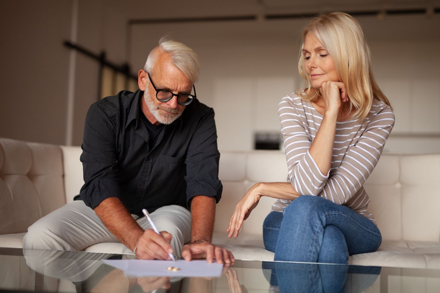 Couple signing papers on a glass table at home