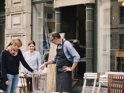 Smiling Retailers Assisting Woman Outside Shop