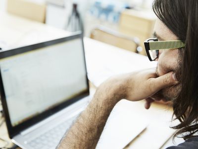 Over shoulder close up of male office worker looking at laptop in office