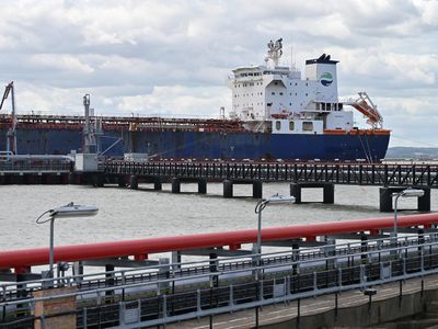 An oil tanker with the Hafnia logo transfers its fuel cargo via pipeline to the shore.