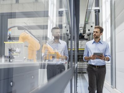 Businessman checking robots with digital tablet in high tech company