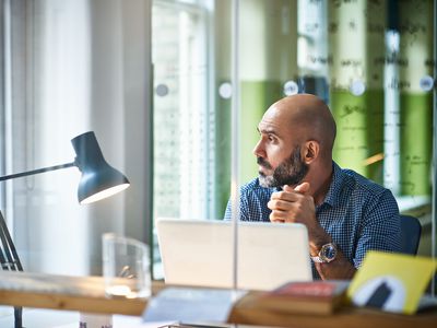 A man sitting at a desk pauses in thought.