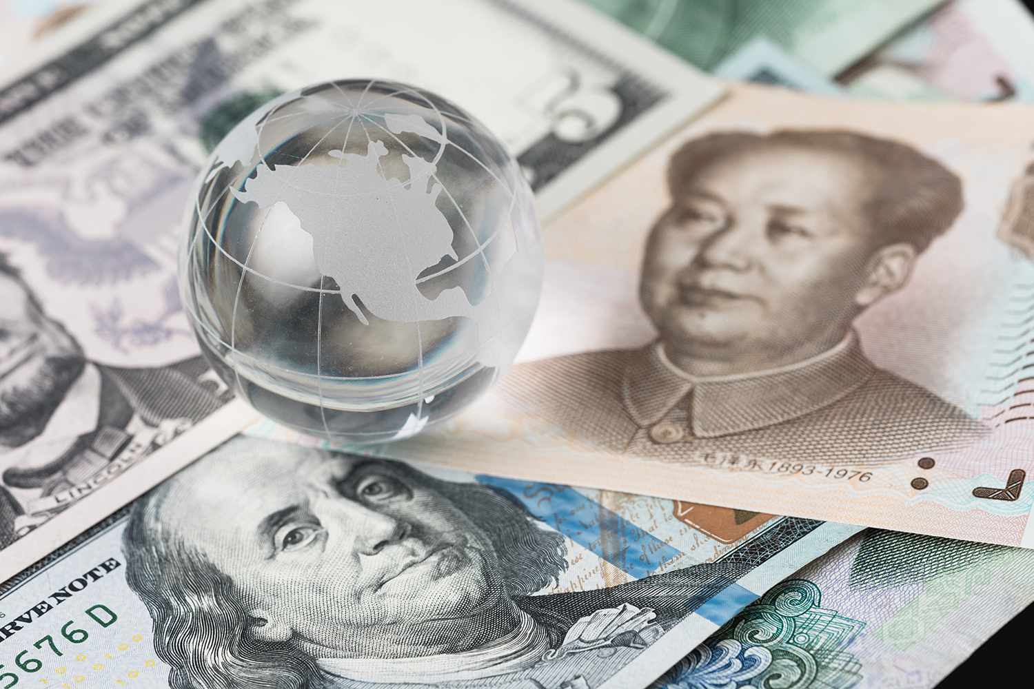US and China trade barrier, an action by a government that makes trade between the country and other countries more difficult, decoraton glass globe on US dollar and china yuan banknotes