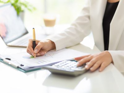 Businesswoman working with business document, calculator, and laptop on table