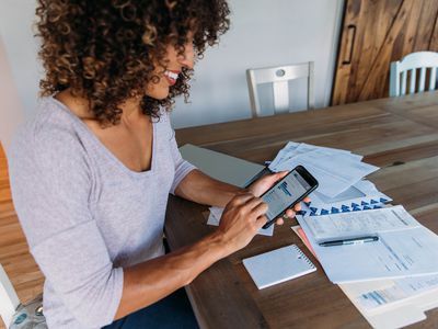 Woman working on her finances at home on her smartphone