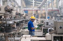 Male worker in a hard hat working amid equipment at a factory