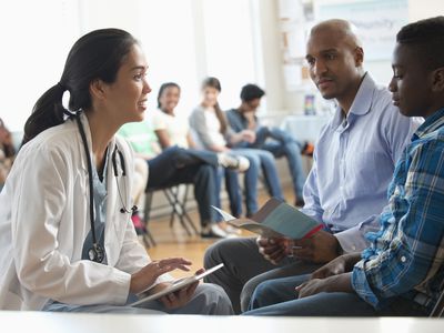 Doctor using digital tablet with father and son in volunteer clinic