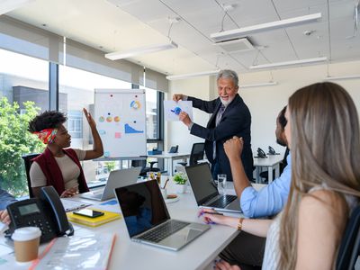 People sitting at a conference table listing to a man presenting