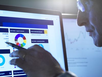 Financial services, stock analyst researching share price data of a company on the computer