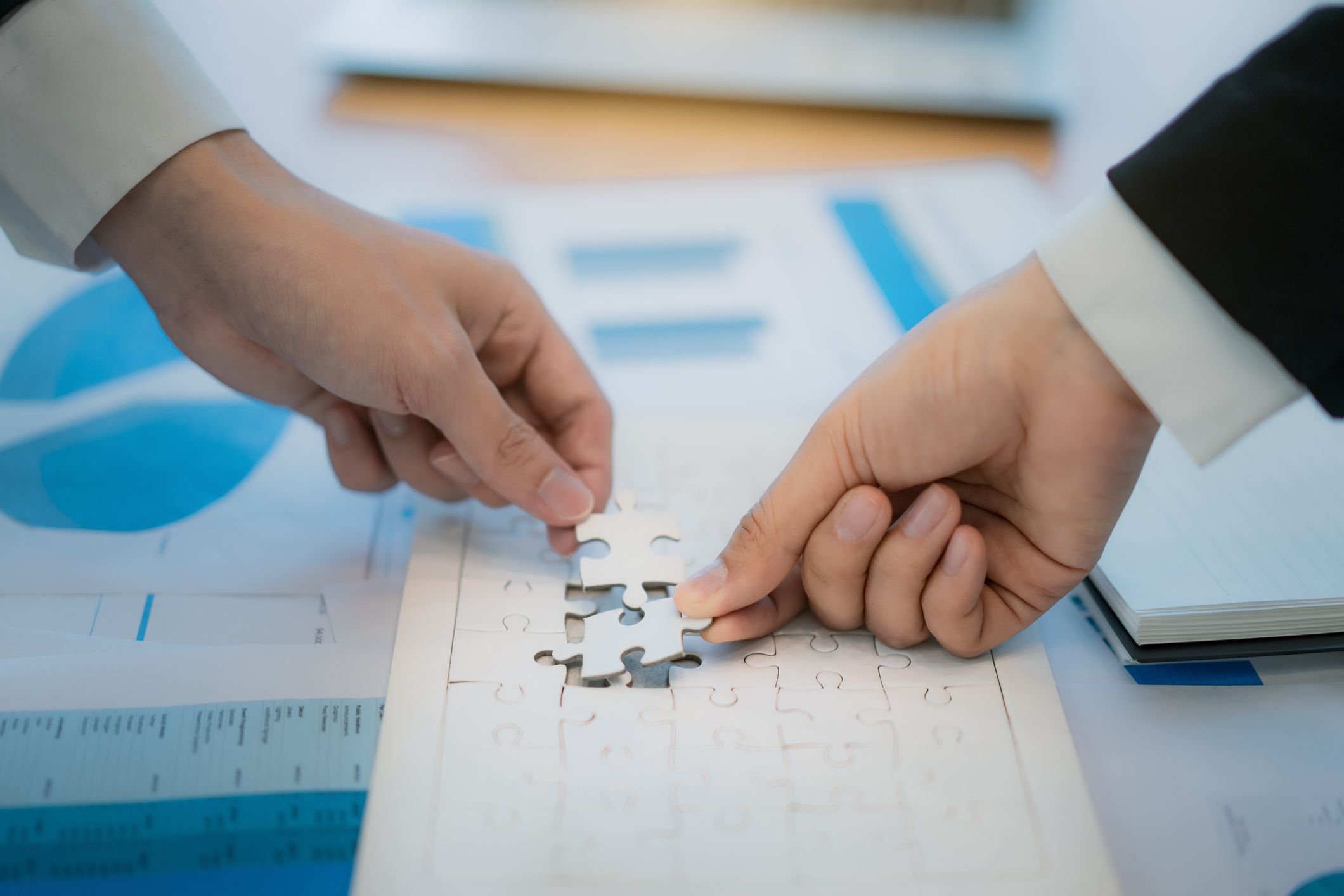 Business people hold paper jigsaw puzzle and solving puzzle together