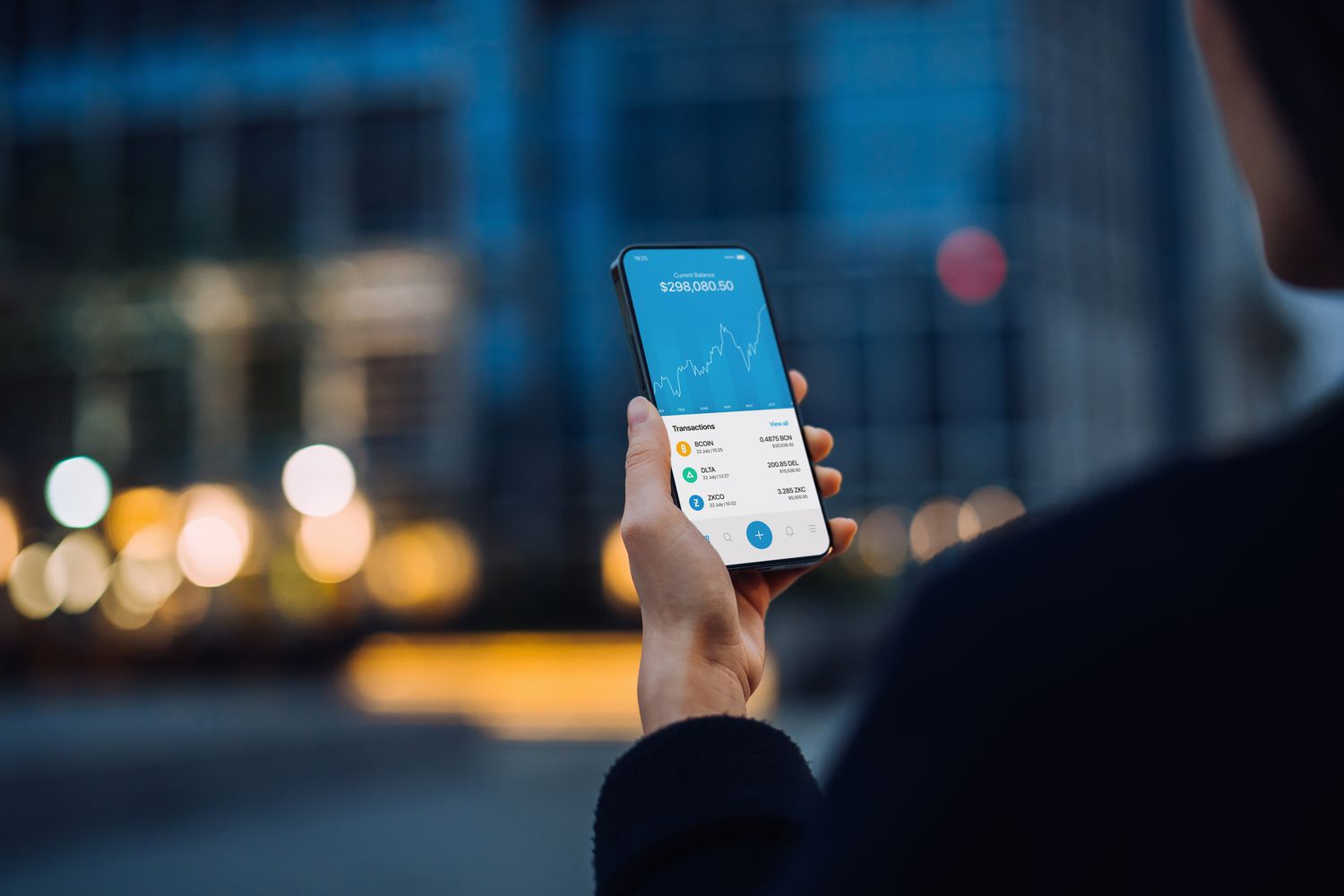 Woman holding a phone that is showing Bitcoin price chart over time