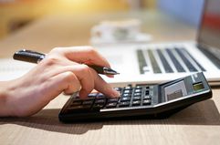 A woman hand working with calculator sitting at a desk.