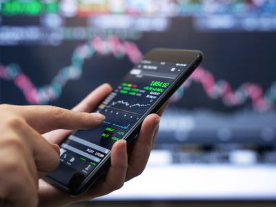 A person holds a smart phone depicting a stock chart