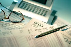 Tax forms, glasses, calculator, pen