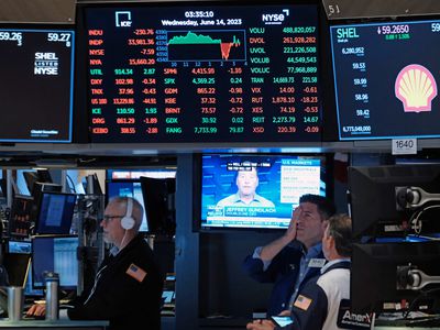 Traders stand beneath screens of stock data on the floor of the New York Stock Exchange