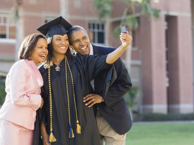 Female African American college graduate taking photo with parents 