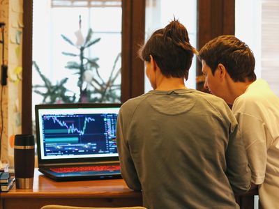 Two people looking at market data on a laptop screen 