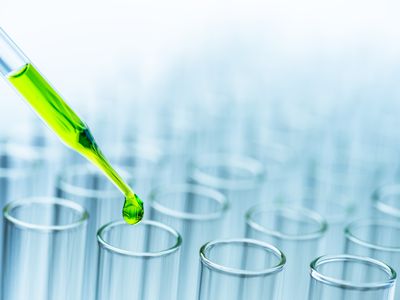 Close-Up Of Green Liquid Pouring From Pipette In Test Tubes