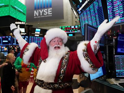 A man dressed as Santa Claus holds his hands up on the floor of the New York Stock Exchange